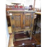 A reproduction oak cupboard, fitted with two carved doors, width 20ins