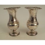 A pair of silver vases, of baluster form, with floral embossed edges, weighted bases, London 1910,