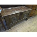 An 18th century oak coffer, having two carved panels to the front with three plain panels to the