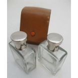 A pair of glass toilet bottles, with white metal caps, within a leather case, bottle dimensions