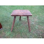 A primitive three legged stool, with turned legs, height 17ins x width 15ins