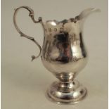 A Georgian silver jug, with shaped edge, raised on a pedestal to a circular foot, London 1774,