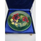 A Moorcroft plate, decorated with hibiscus to a green ground, with signature, impress mark and paper