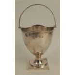 A silver standing bowl, with swing handle, shaped edge, raised on a pedestal to a square foot,