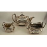 A Georgian silver three piece tea set, the tea pot with serpent finial, bands of gadrooned