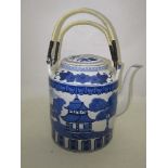 An over-sized Chinese tea pot, decorated in blue and white, with pagodas in an all around landscape,