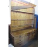 An Antique pine dresser, with rack back, the base fitted with an arrangement of drawers around a
