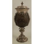 An Edwardian silver mounted coconut cup and cover, the coconut carved with flowers, a bird and