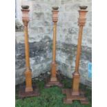 Three oak candlestands, the brass candle holders raised on oak columns, one with Ionic capital,