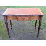 A mahogany fold over games table, with carved edge, fitted with a frieze drawer, raised on fluted