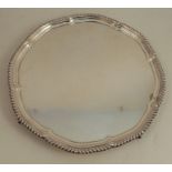 A silver salver, with gadrooned shaped edge, raised on four ball and claw feet, Sheffield 1932,