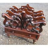 A Victorian rosewood Canterbury, the four divisions carved with scrolls and leaves, fitted with a