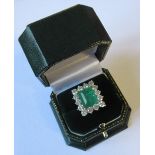 An emerald and diamond cluster ring, in an unmarked white mount, the step cut emerald measuring