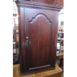 An Antique oak corner cupboard, the door opening to reveal shaped shelves, height 45ins, width