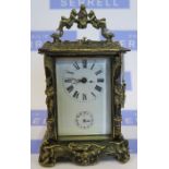 A reproduction brass carriage clock, the case decorated with figures and scrolls, height including