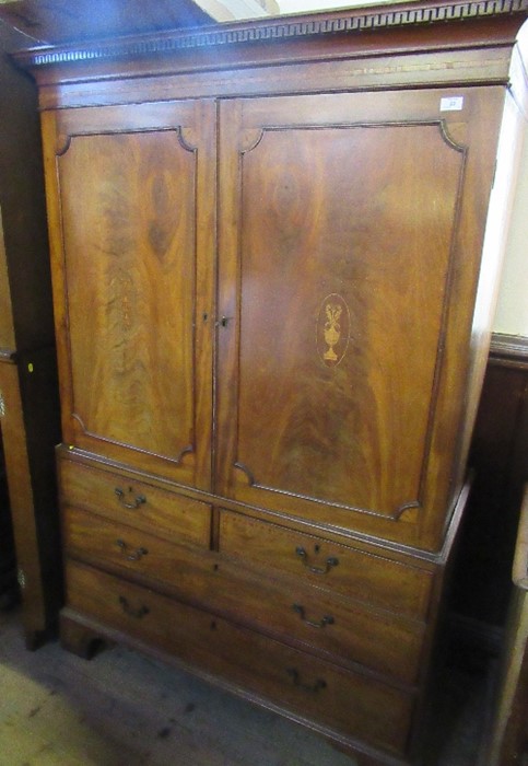 A 19th century mahogany linen press, the pair of cupboard doors with inlaid decoration, opening to