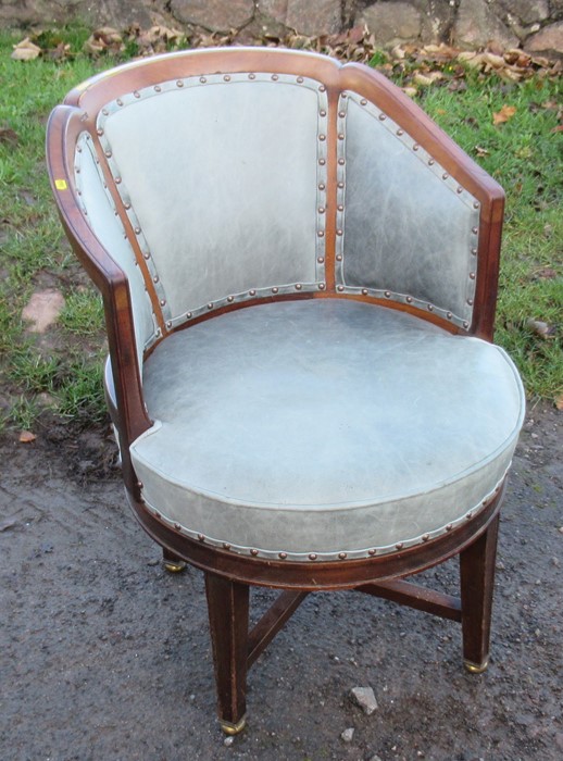 A mahogany framed and leatherette upholstered revolving office chair, raised on four legs united