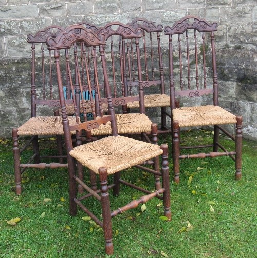 A set of six oak dining chairs, with carved top rail over spindles with rush seat