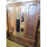 An oak triple door wardrobe, the central door with mirror opening to reveal a double hanging