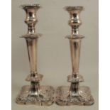 A pair of silver candlesticks, with embossed flower decoration, raised on shaped square bases,