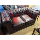 A Two Seater Chesterfield with matching armchair in oxblood leather upholstery