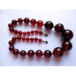 A Graduated Faux Cherry Amber Bead Necklace, 55cm, 109g, largest bead 28.5mm