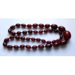 A Graduated Faux Opaque Cherry Amber Bead Necklace, c. 89cm long, 92.6g, largest bead 35x24mm
