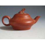 An Antique Chinese Yixing Teapot, the rim decorated with character marks and the lid with a seated