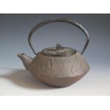 A Chinese Cast Iron Swing Handled Teapot with various cast character marks, 16cm high