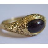 A Georgian Foil Back Cabochon Purple Garnet Ring in a high carat unmarked gold setting with chased