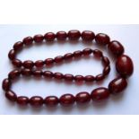 A Graduated Faux Opaque Cherry Amber Bead Necklace, c. 74cm long, 97g, largest bead 33x24mm