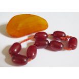 A Baltic Amber Brooch 48x27mm 10.4g and faux cherry amber beads 8.6g