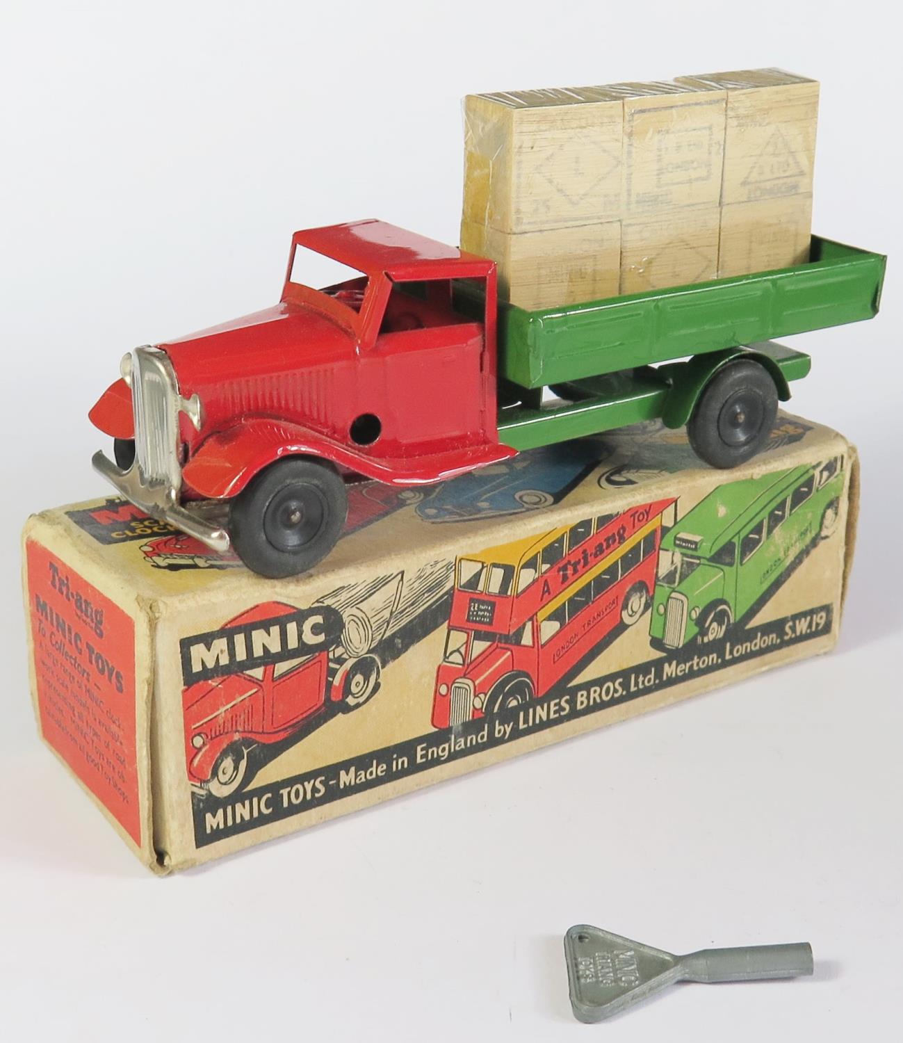 A Triang Minic Clockwork Delivery Lorry in red and green with black hubs. It is in near mint working