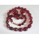 A Faux Cherry Amber Faceted and Graduated Bead Necklace, 76cm largest bead 30x25mm 174g with