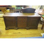 A Georgian Oak Breakfront Sideboard with three central drawers and cupboards flanked by quarter