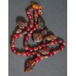 A Carved Amber Necklace (thread broken), carved amber beads and two small carved amber figures,