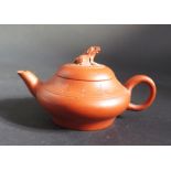 An Antique Chinese Yixing Teapot, the rim decorated with character marks and the lid with a seated