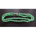 A Good Twin Strand Jadeite Bead Necklace with a rose cut diamond and carved jadeite clasp in an