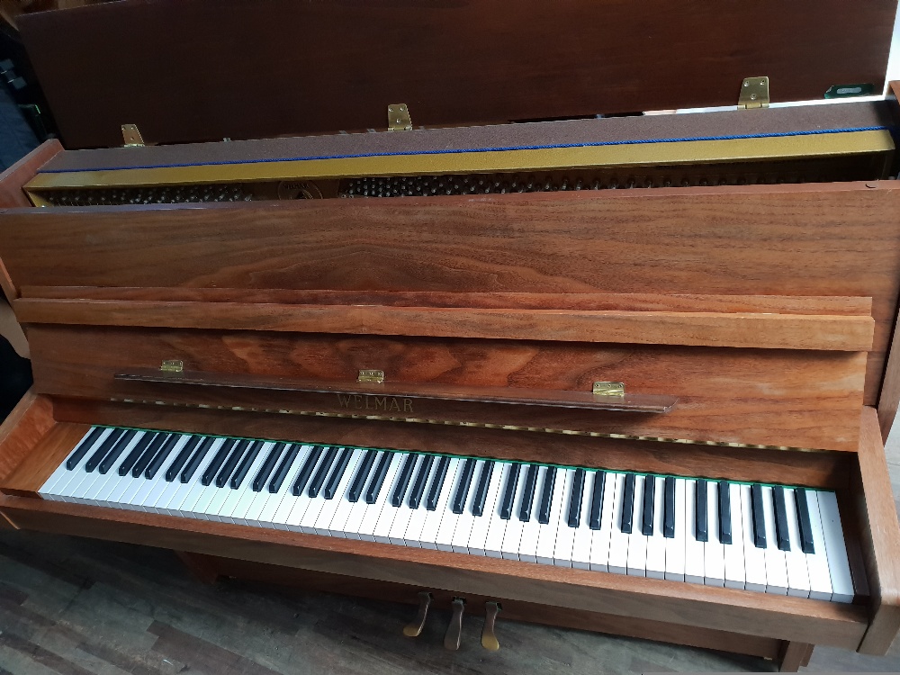 Welmar (c1994) An upright piano in a modern style mahogany case. AMENDMENT Is in a walnut case.