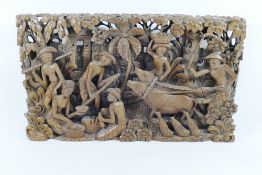 An Indonesian carved and pierced wooden storyboard panel, depicting figures and animals,