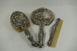 An Art Nouveau silver backed three piece dressing table set, comprised of brush,