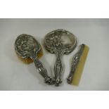 An Art Nouveau silver backed three piece dressing table set, comprised of brush,