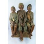 A large Goldscheider pottery model of three boys sitting on a brick wall by B Haniroff,