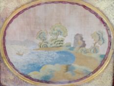 A 19th century embroidered oval silk work panel of a ruin by a lake with a sailing boat,