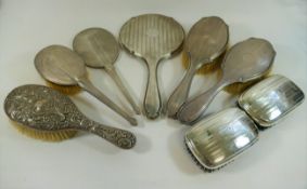 A silver backed three piece dressing table set comprised of a pair of brushes and a hand mirror,