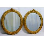 A pair of oval gilt framed mirrors, the gesso frames with floral, beaded and cartouche decoration,