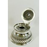 A late Victorian silver circular ink well, with half reeded body and hinged lid,