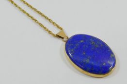 A 9 carat gold lapis lazuli oval pendant, London 1977, 4cm x 3cm, on yellow metal chain,