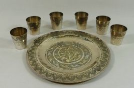 A set of six silver coloured metal tots and matching circular tray,