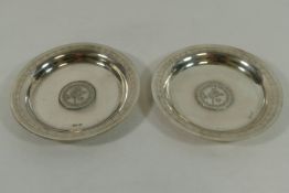 A pair of small circular silver coloured metal dishes,